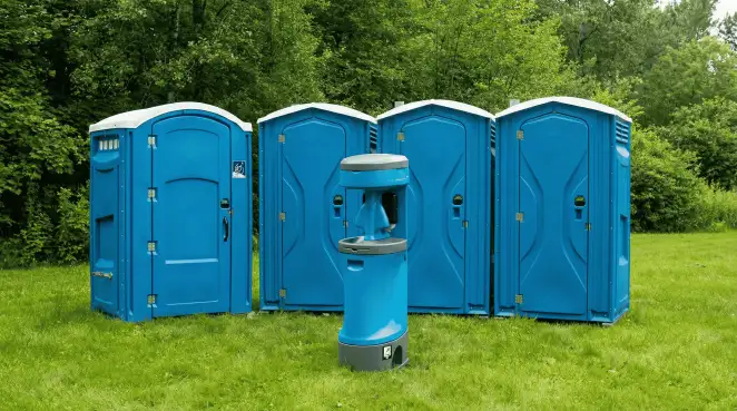 Four blue portable toilets and a matching hand washing station on grass near trees, a common sight at local outdoor events in Marietta, GA